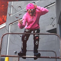 a man in a pink hoodie standing on a metal railing