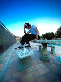 a man sitting on a bench next to a pool
