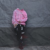 a person in a pink hoodie leaning against a wall