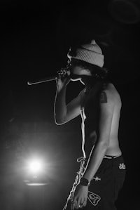 a shirtless man holding a microphone in front of a light