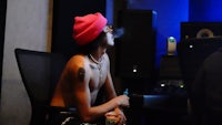 a man in a pink hat smoking a cigarette in a recording studio