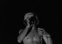 a shirtless man holding a cell phone in the dark